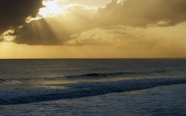 Sun rays breaking through clouds over the open Bali Sea in the evening