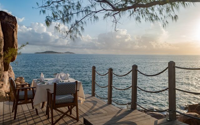 Romantic dinner table on a wooden deck overlooking a tropical sea