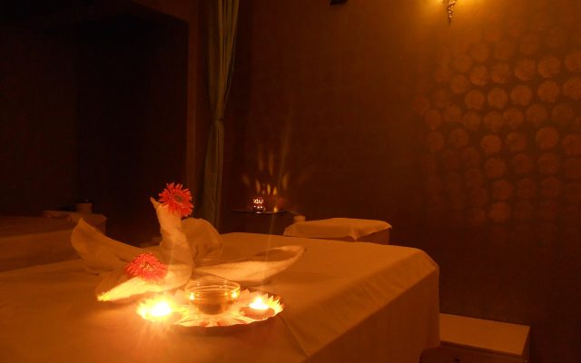 Massage beds and candles with flower petals in a warmly lit spa room