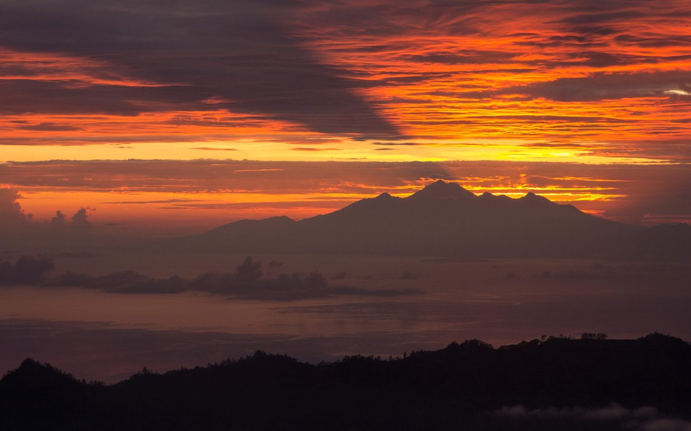 Red and orange dawn sky over distant volcano peaks seen from Mount Batur