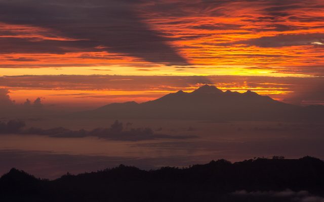 Red and orange dawn sky over distant volcano peaks seen from Mount Batur
