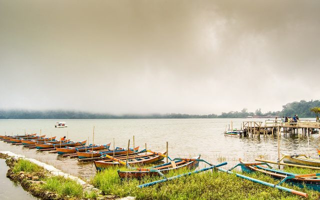Traditional boats moored along the shore of misty Lake Bratan in the Bedugul highlands