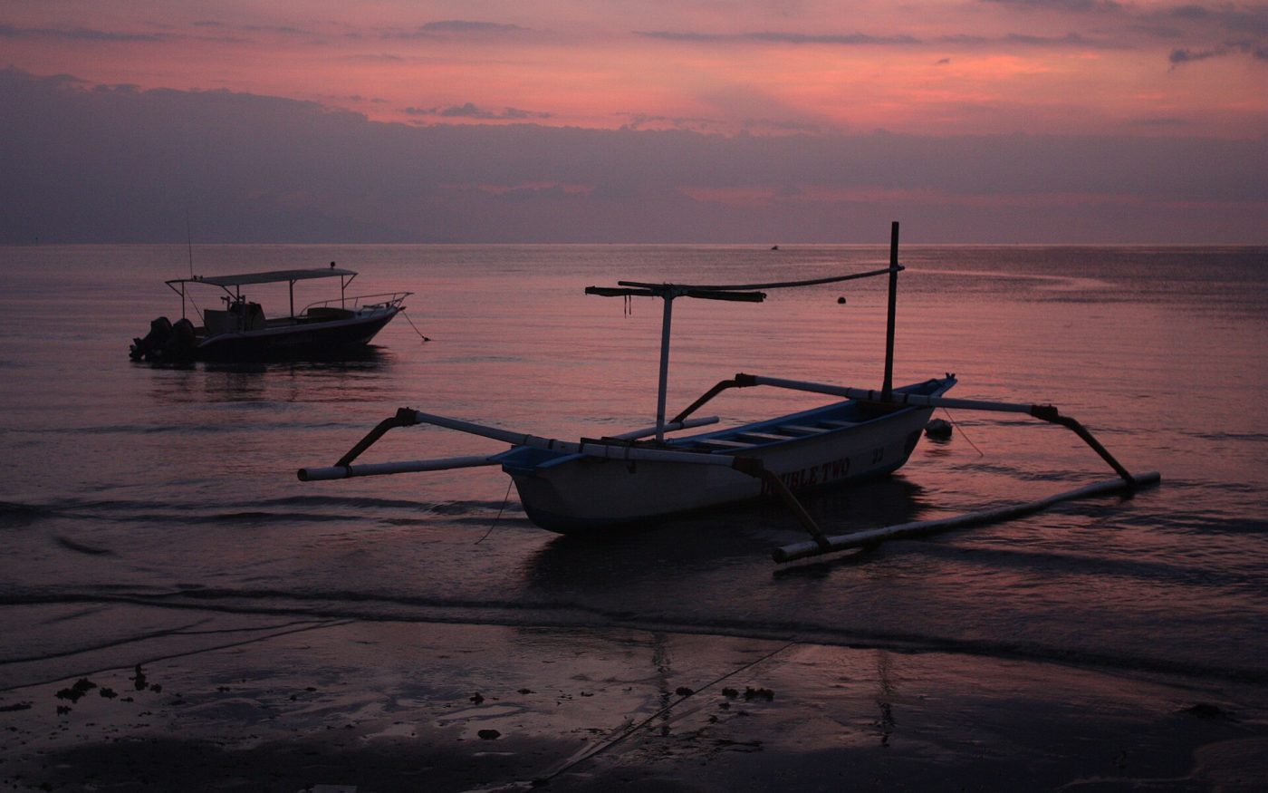 Traditional Balinese outrigger jukung boat silhouetted on Lovina beach at dusk