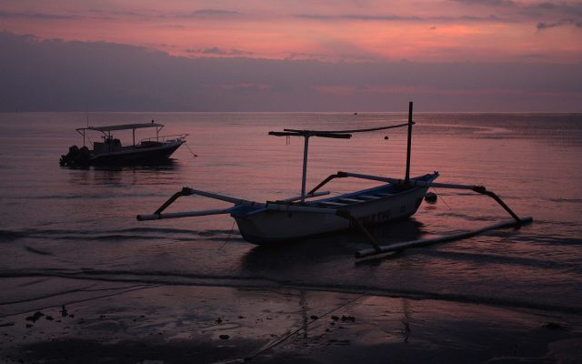 Traditional Balinese outrigger jukung boat silhouetted on Lovina beach at dusk