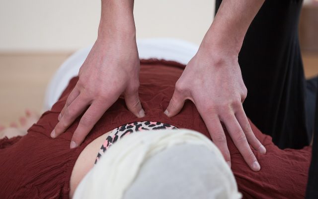 Therapist applying palm pressure along the back of a fully clothed client during a shiatsu session