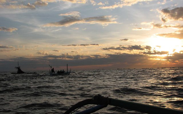 Outrigger boats waiting for dolphins under the rising sun off the Lovina coast