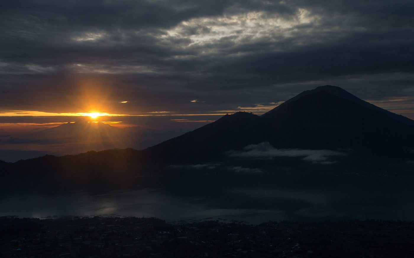 Sun rising beside a volcano silhouette above the Batur caldera, seen from Mount Batur
