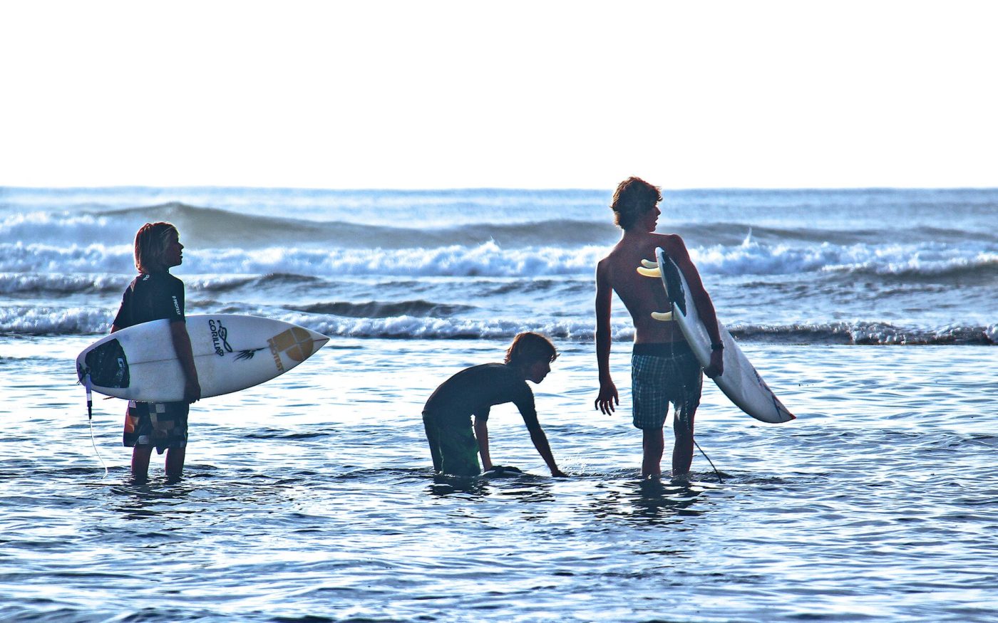 Young surfers with surfboards in the waves at a beach in Bali