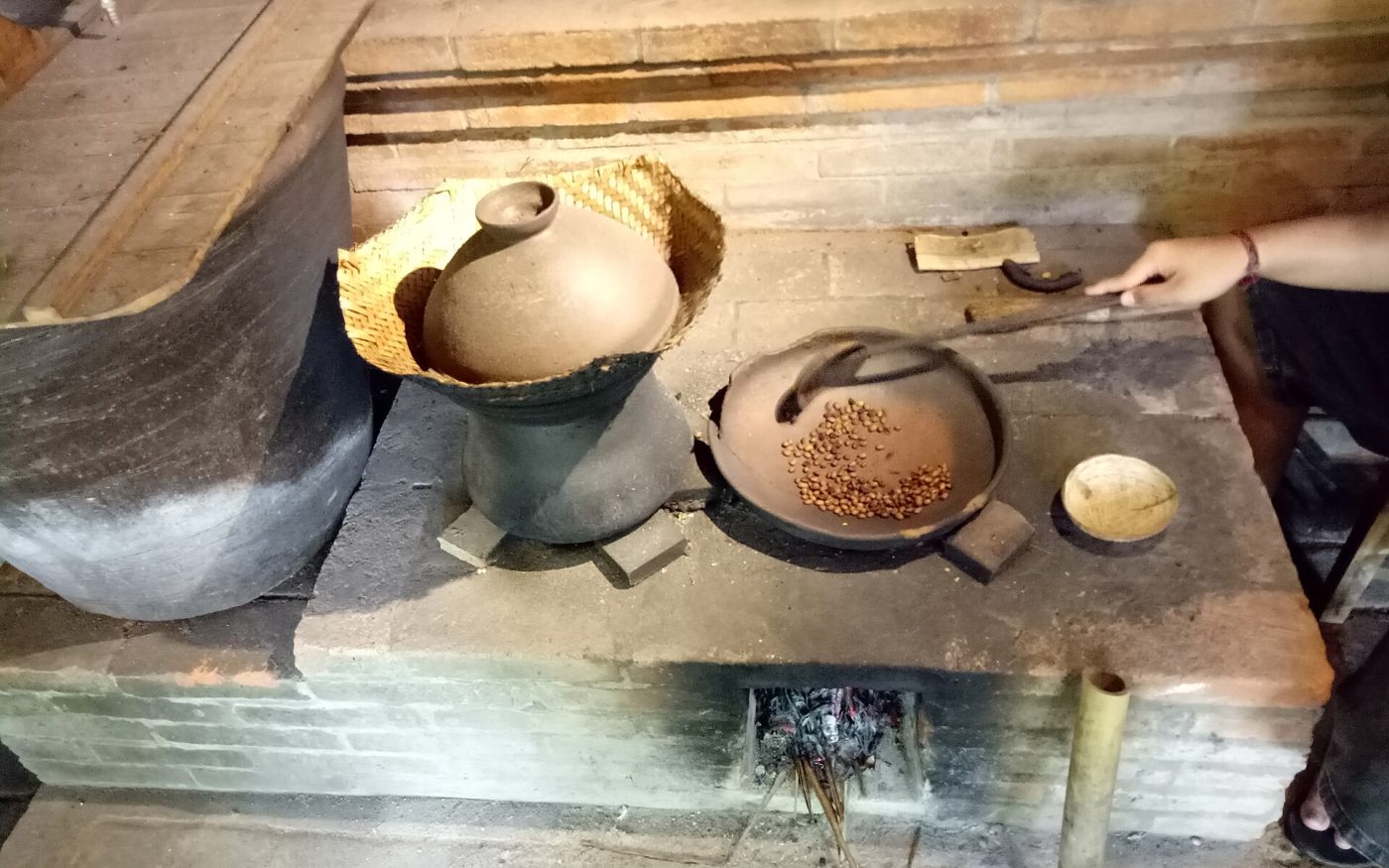 Coffee beans being roasted in a clay pan over a wood fire at a Balinese coffee plantation